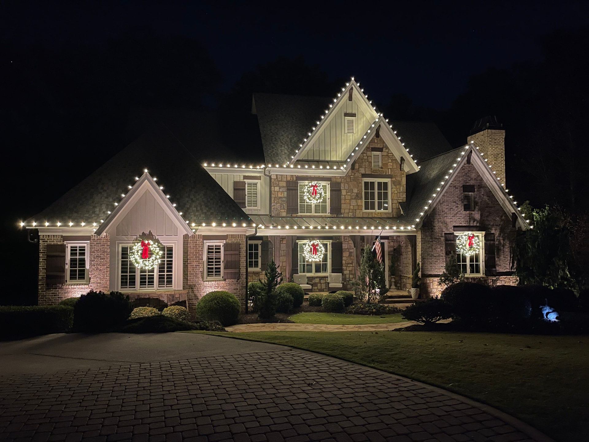 Home glowing with roofline and porch Christmas lights at night